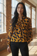 Blouse Anthiope à motif géométrique moutarde et bleu marine avec col lavallière et manches longues fluides