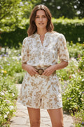 Combishort Anthiope beige et blanc à imprimé floral, col officier, manches bouffantes et ceinture tressée en jardin