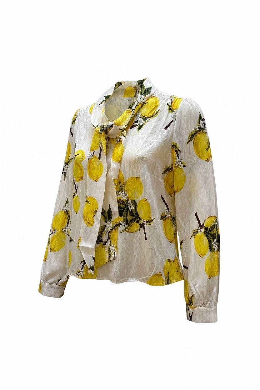 Anthiope long-sleeve blouse in white with a vibrant yellow lemon print and a decorative neck tie detail.